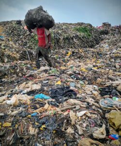 Un récupérateur transporte sur la tête un sac rempli de bouteilles plastiques après plusieurs heures de collecte.
